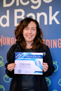 Maken Rutan, School-Based Programs Coordinator, holds the 2025–26 Community Partner of the Year certificate awarded to the San Diego Food Bank by Naranca Elementary School.