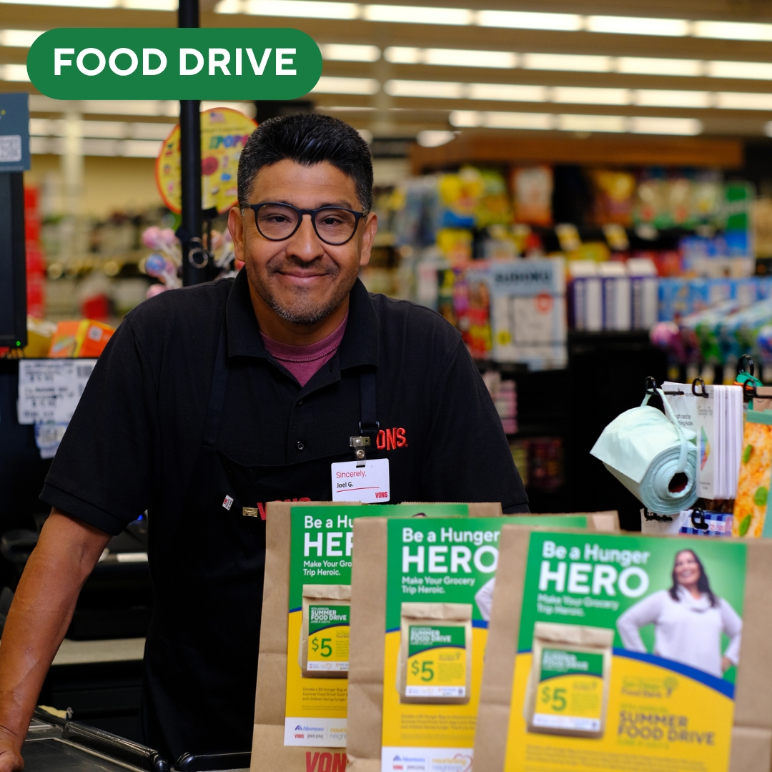 A cashier at Vons in front of hunger bags for the Summer Food Drive.