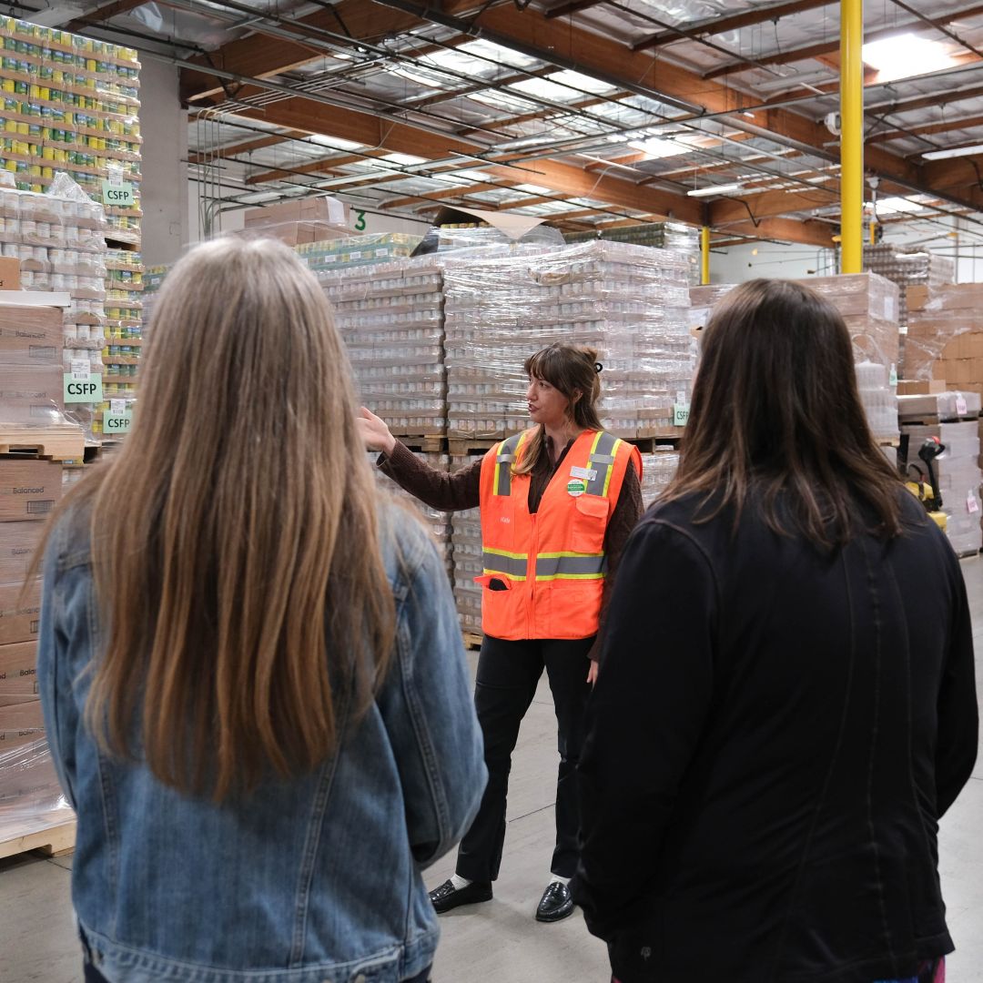 A staff member leading a tour and pointing out objects in our warehouse.