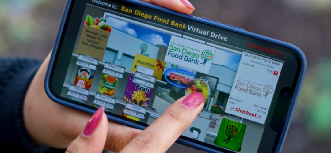 A hand donating food through the virtual food drive online store.