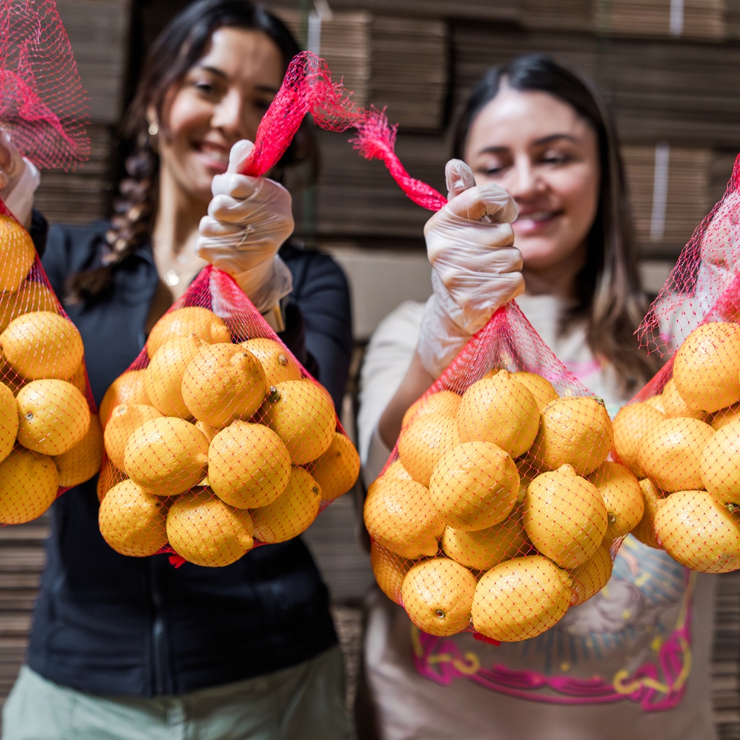 Two volunteers holding up bags of lemons.