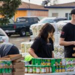 Volunteers arrange boxes of nonperishable items at a local food distribution.