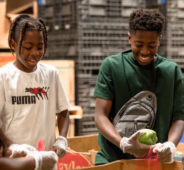 Volunteers in our warehouse bagging peppers.