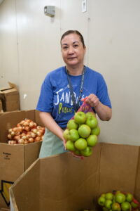 Claudia, librarian at San Diego Public Library, holds a bag of green apples.